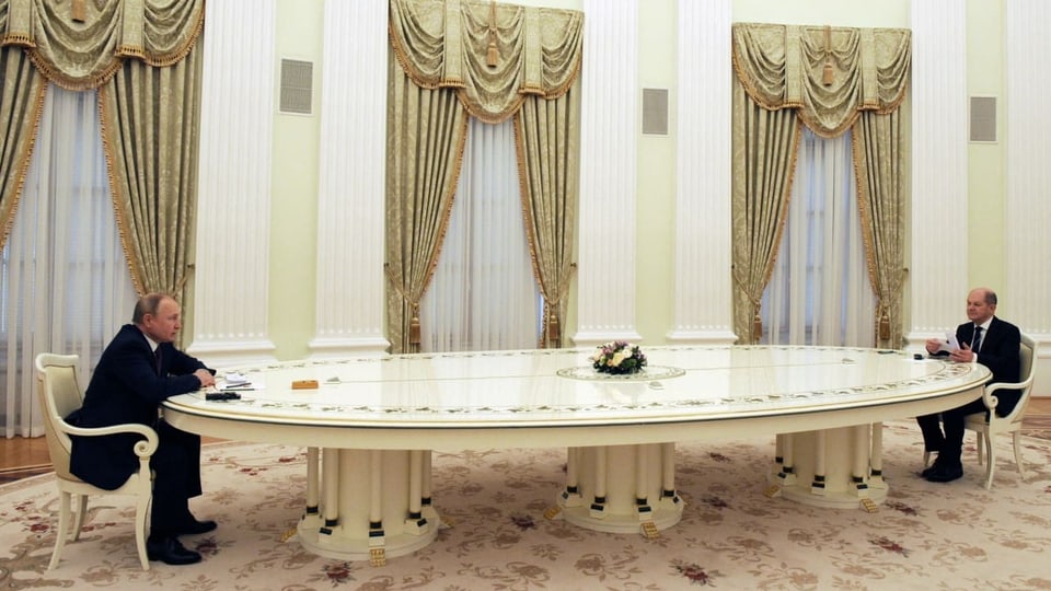 Putin und Scholz sitzen an einem langen Tisch.