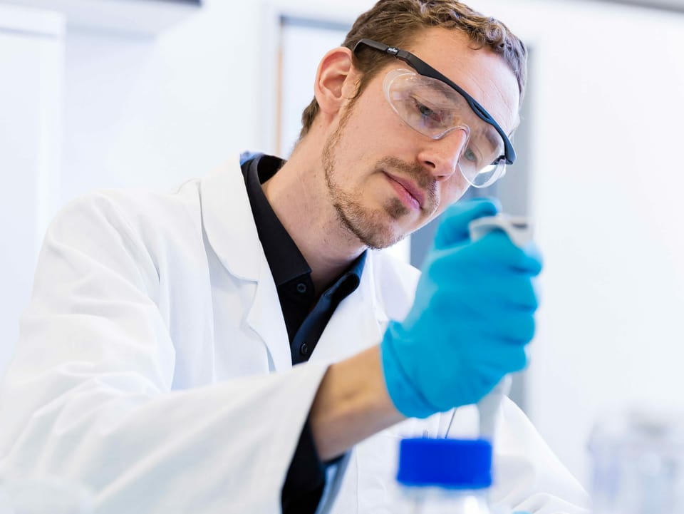 Forscher im Labor mit Kittel und Handschuen