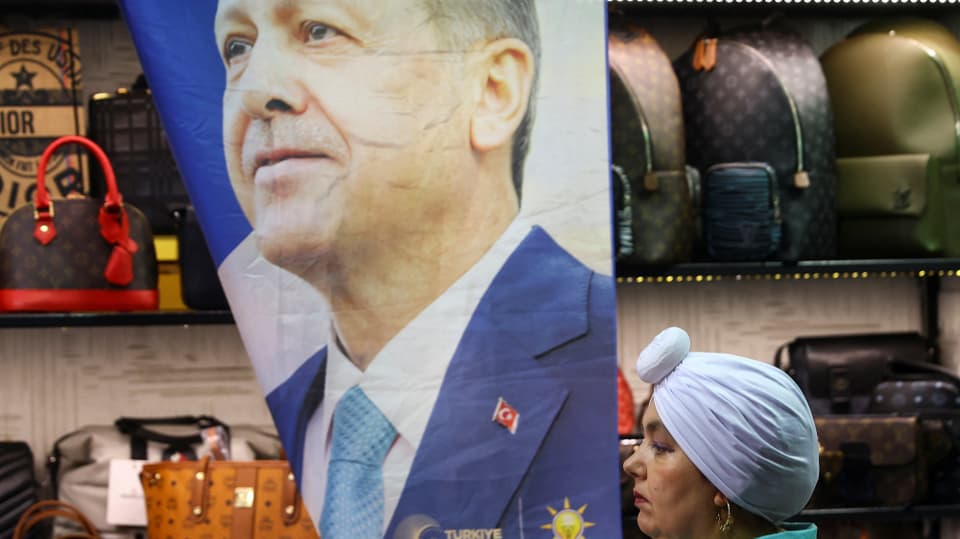 Erdogan blickt auf einem Plakat in die Ferne, davor geht eine Frau vorüber.