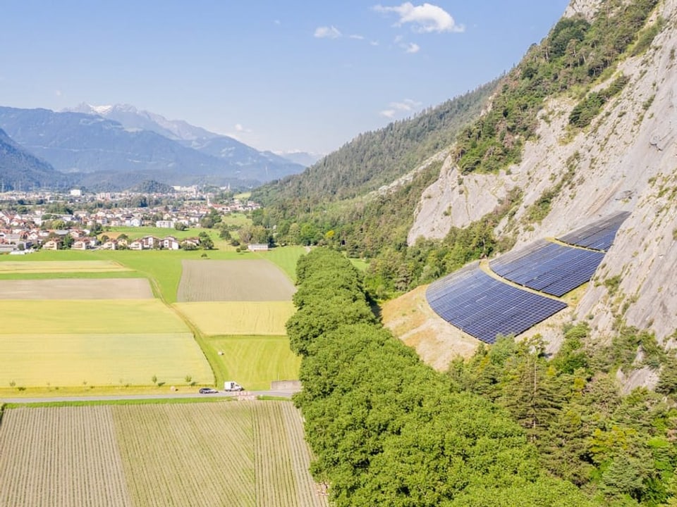 Solarpanels an einem Hang unterhalb von Felsen.