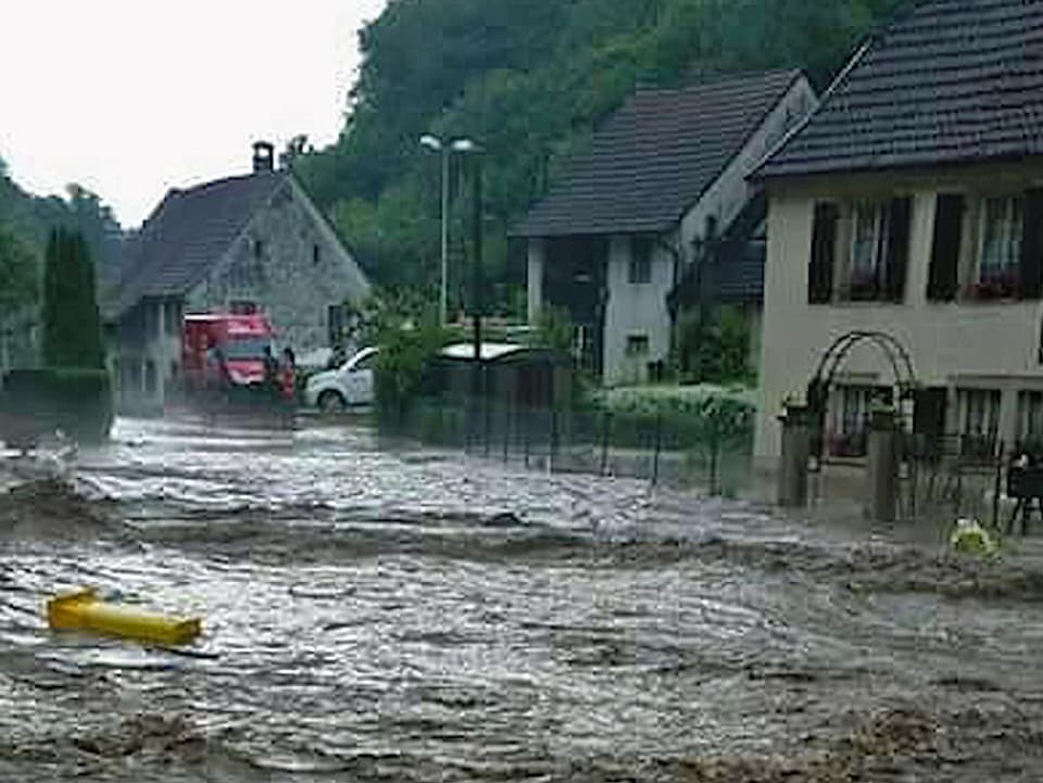 Überflutete Strasse in einem Dorf im Jura.