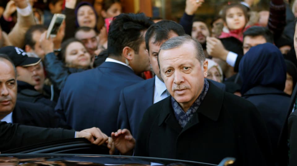 Erdogan steigt inmitten einer Menschenmenge in ein Auto ein.