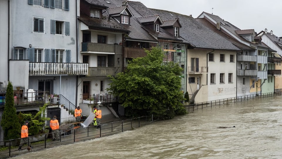Männer von Zivilschutz und Feuerwehr errichten Hochwasserschutz bei Altstadt-Häusern, das Wasser ist bereits sehr hoch.
