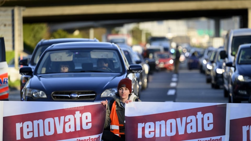 Ein Klimaaktivist sitzt auf der Strasse und blockiert den Verkehr.