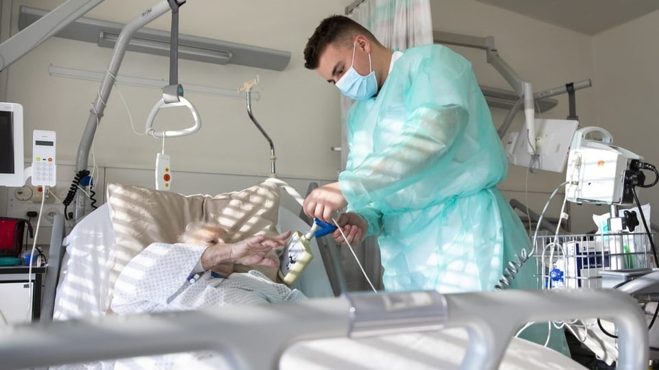 Pfleger betreut alte Frau in Krankenhausbett