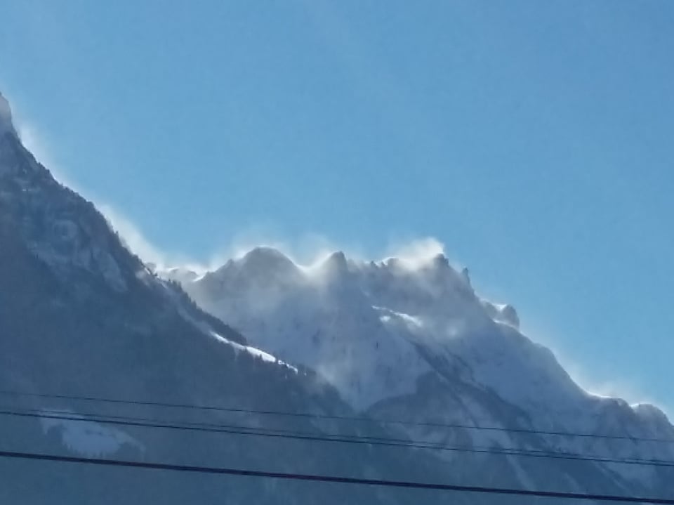 Berge, blauer Himmel und Schneeverwehungen an den Gipfeln.