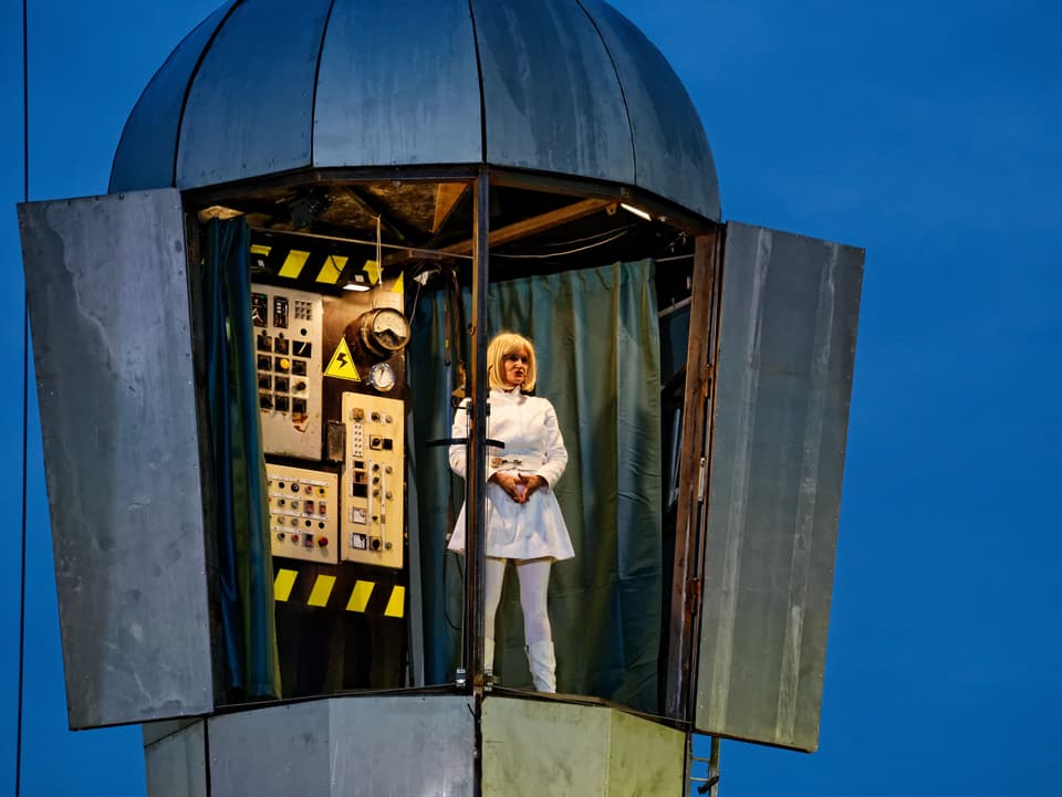 weissgekleidete Frau auf einem Turm mit Schaltzentrale