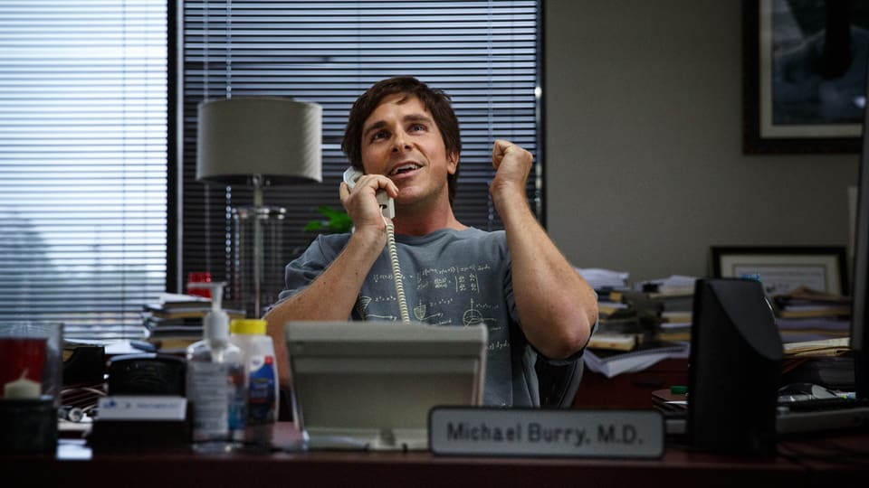 Schauspieler Christian Bale hinter einem Schreibtisch am Telefon.