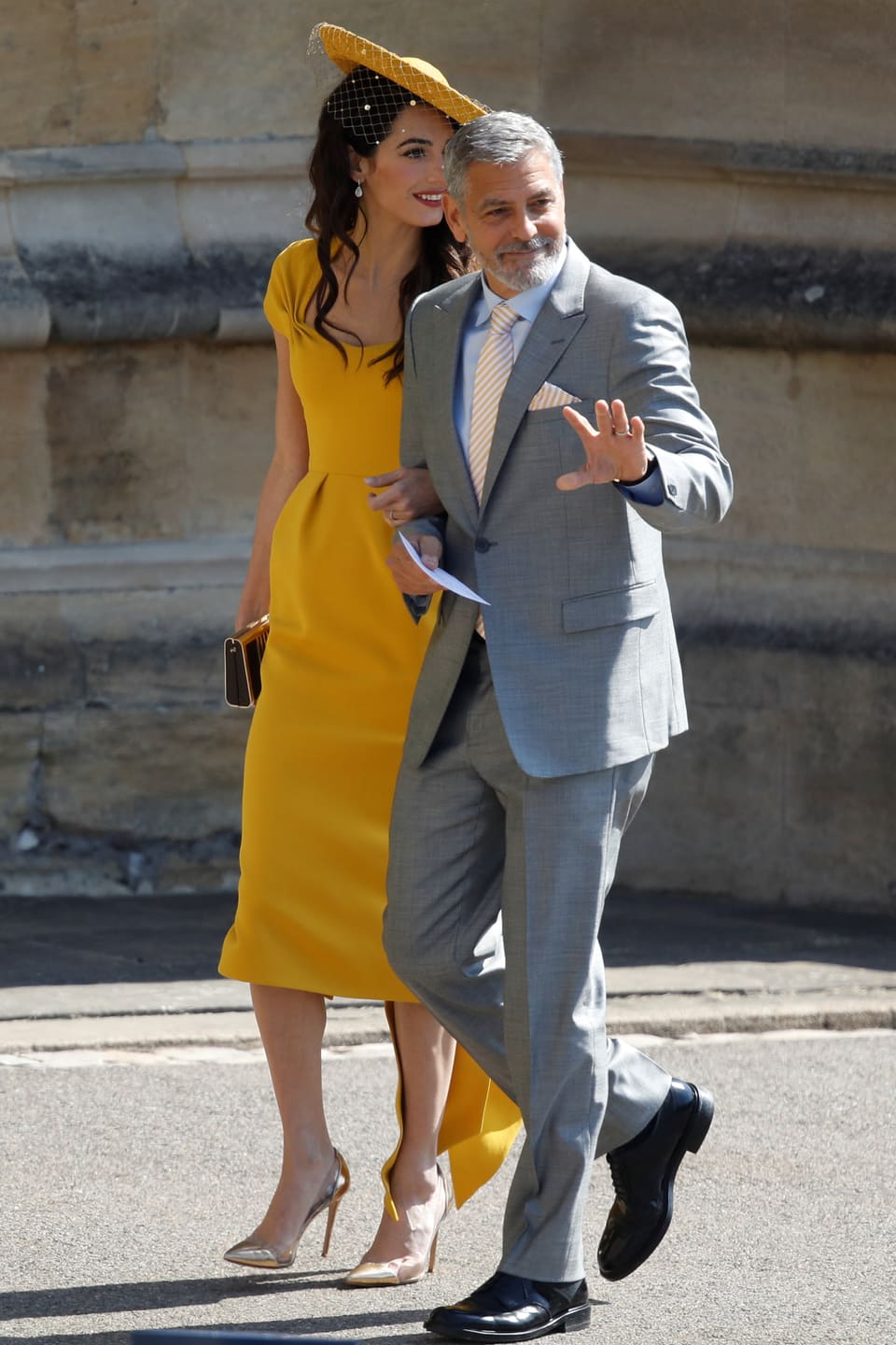 Amal Clooney im gelben Kleid und George Clooney im hellgrauen Anzug