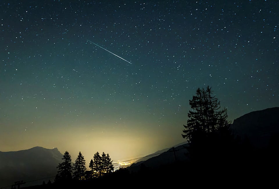 In den Flumser Bergen in der Nacht mit sternenklaren Himmel und einer Sternschnuppe.