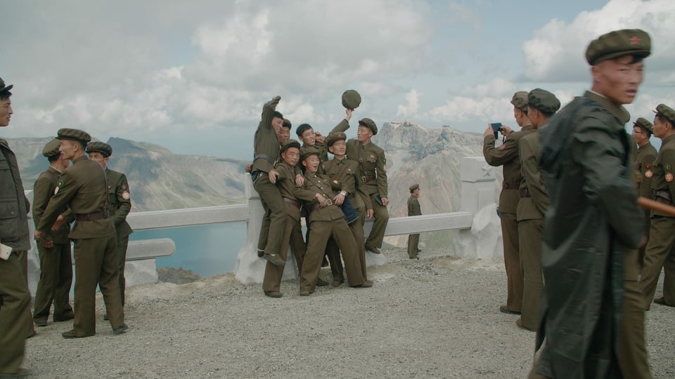 Jugendliche in Militär-Uniform posieren lächelnd vor einem Bergsee