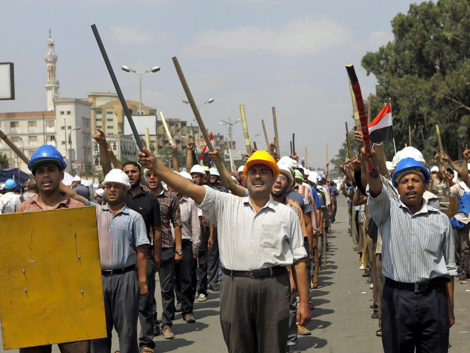 Mursi-Anhänger schreiten mit Schlagstöcken und Bauhelmen zum Präsidenten-Palast in Kairo. (keystone) 