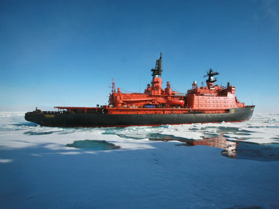 Ein roter Eisbrecher durchkreuzt das Arktische Meer.