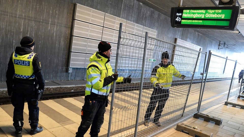 Polizistien stellen Gitter auf an einem Bahnhof.