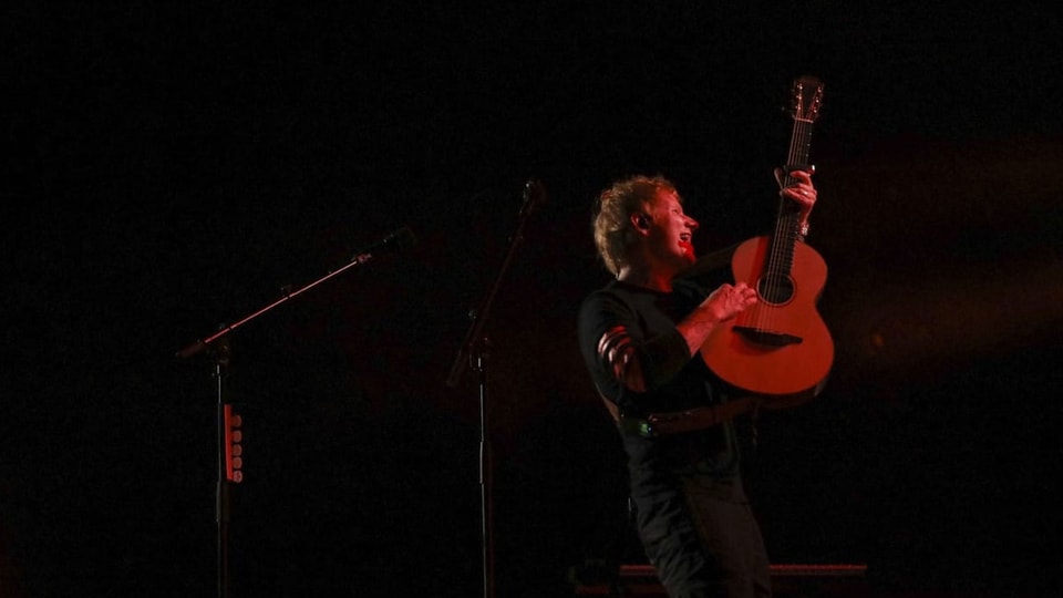 Ein Mann mit Gitarre auf einer Bühne.