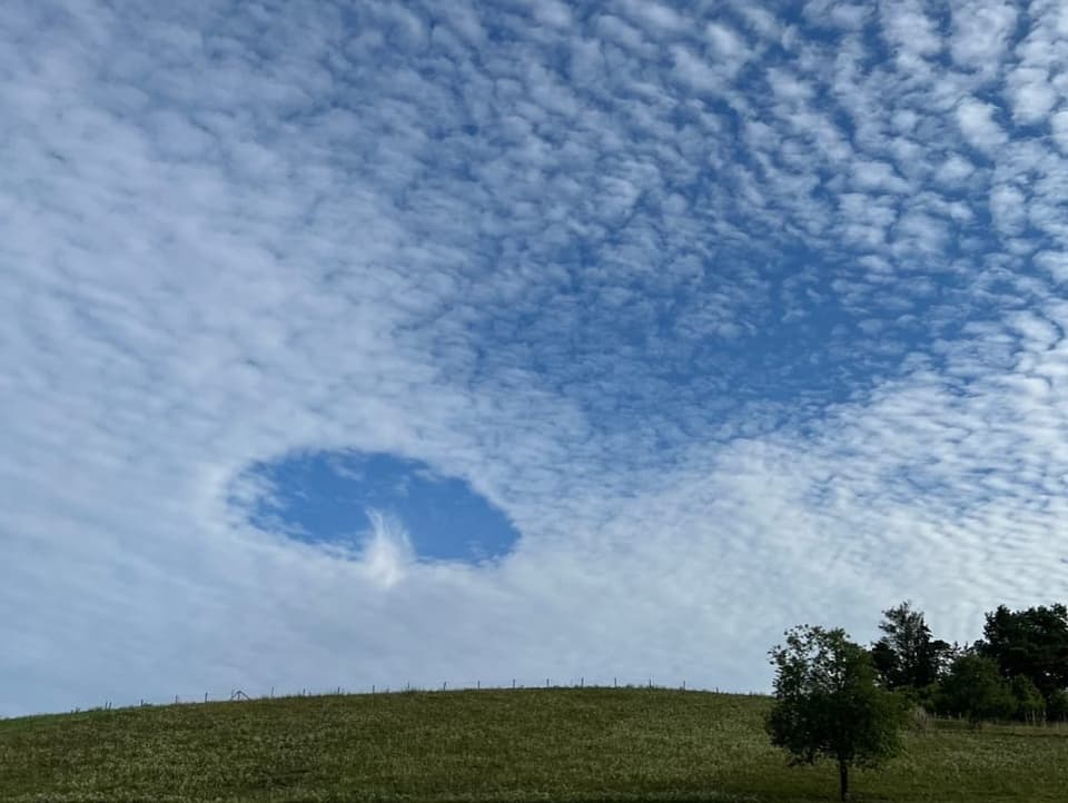 Himmel mit Wolkenfeldern. An einem Ort gibt es ein blaues Loch, in dem eine kleine Federwolke zu sehen ist. 