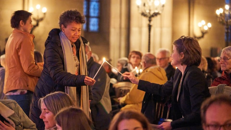 Zwei Frauen in der Kirche übergeben sich das Kerzenlicht.