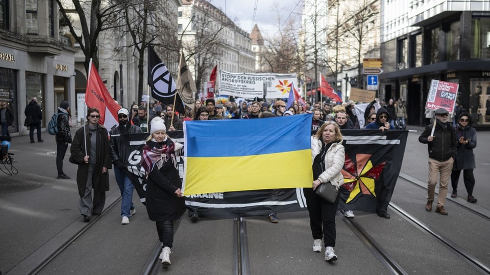 Demonstrierende Personen mit blau-gelber Ukraine-Flagge.