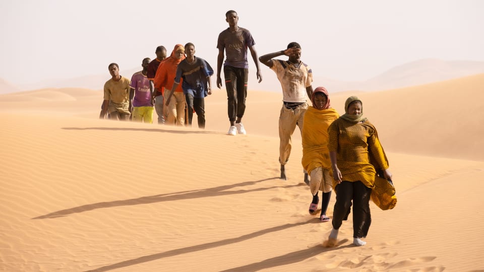 Mehrere Menschen wandern durch den Sonnenschein der Wüste.