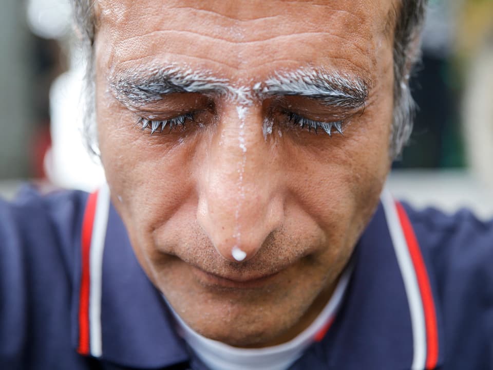 Ein Mann hat sich Milch über des Gesicht geleert, gegen das Tränengas