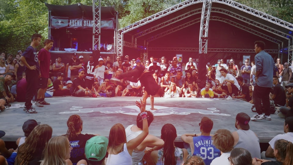 eine Arenaförmige Bühne, umringt von Menschen die ein Breakdance Battle verfolgen