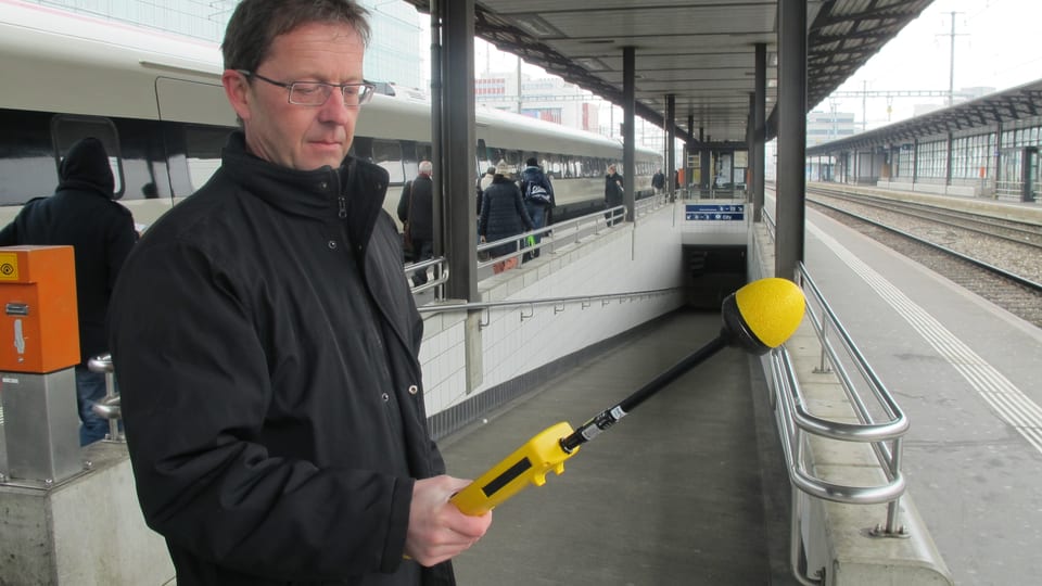 Markus Gugler mit seinem gelben Messgerät mit einer Art Mikrofon am Bahnhof-Perron in Aarau.