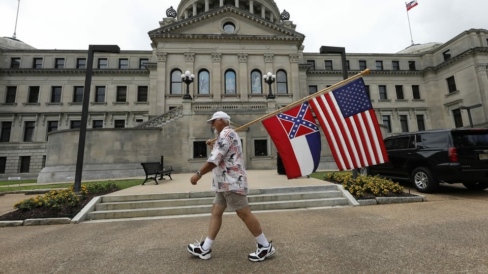 Ein Mann mit einer Flagge Mississippis und der US-Flagge
