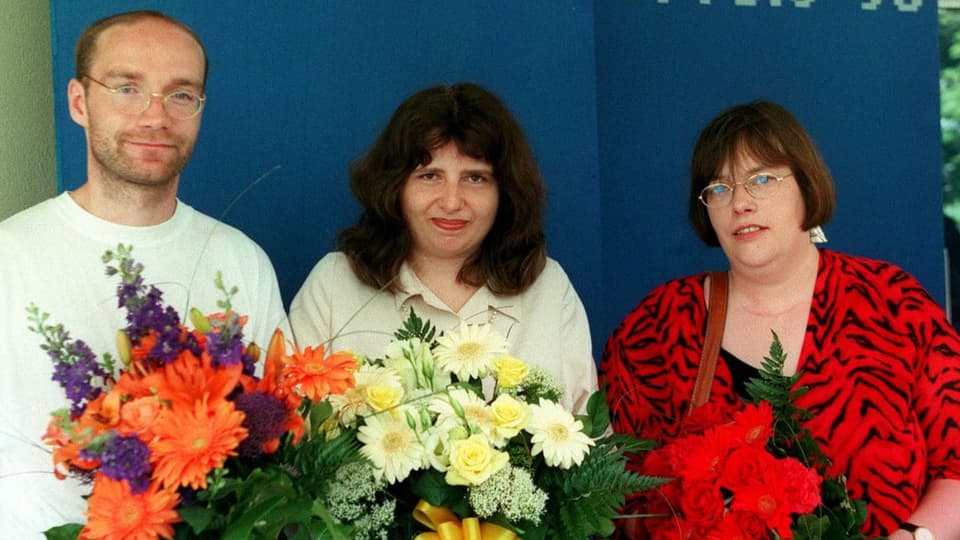 Sibylle Lewitscharoff zwischen zwei Kolleg:innen mit einem Blumenstrauss in der Hand.