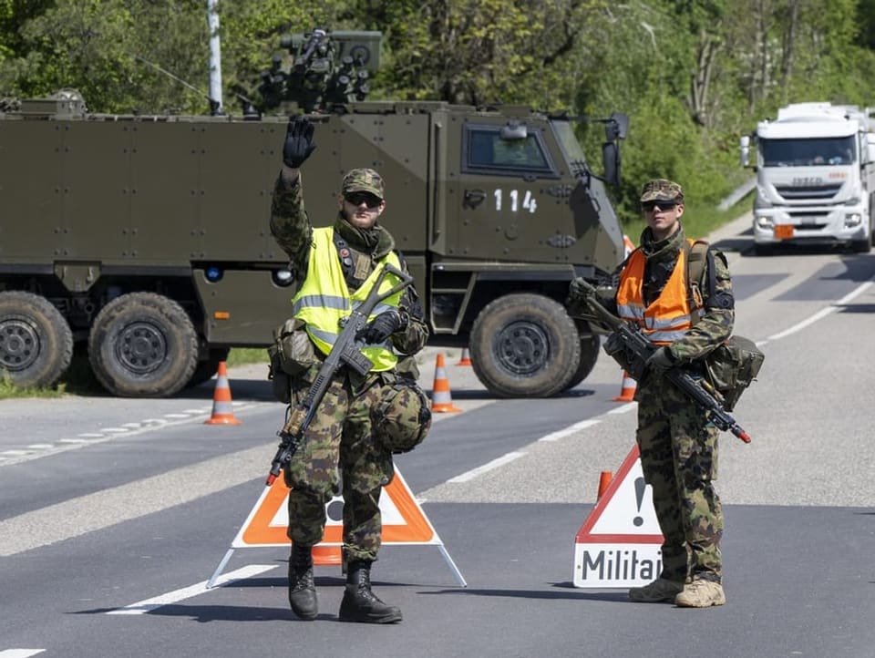 Zwei Militärs auf der Strasse. Ein Armeefahrzeug steht quer.