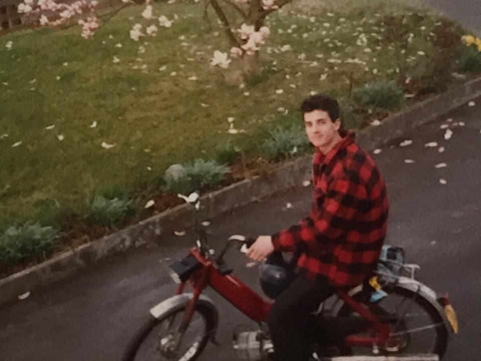 Philippe Gerber sitzt mit einem Flanellhemd bekleidet auf einem Moped.