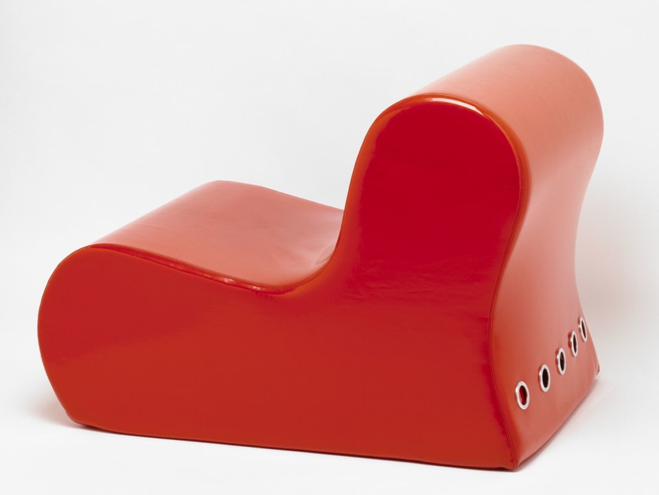 Ein L-förmiger, roter Stuhl.