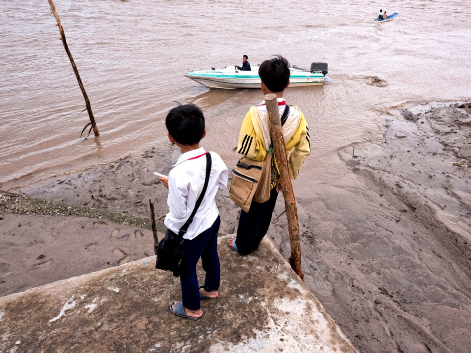 Kinder stehen am Fluss.