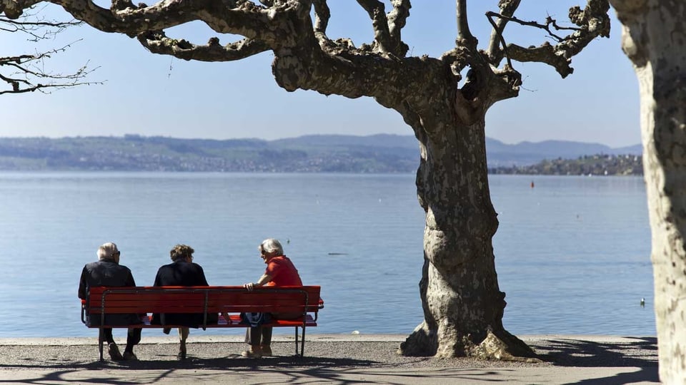 Senioren sitzen in Rapperswil-Jona (SG) am Ufer des Zürichsees auf einer Bank. (Keystone)