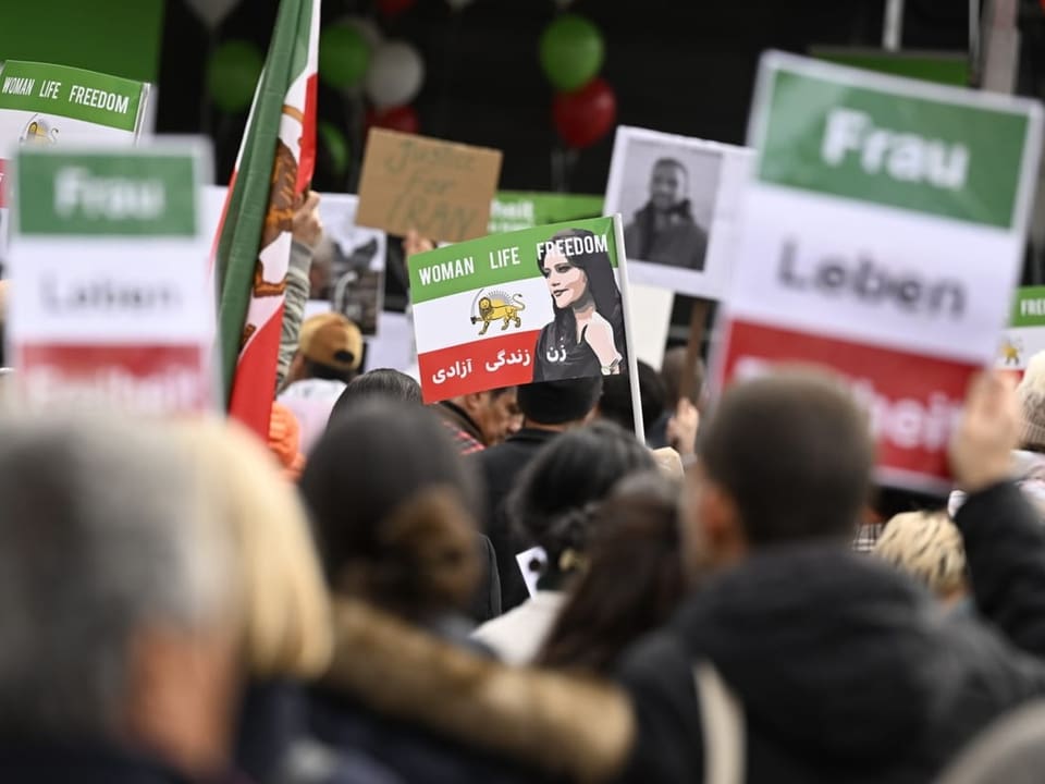 Menschen protestieren mit Plakaten und Iran-Fahnen.