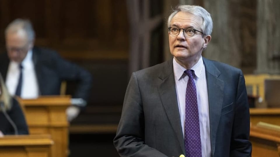 Älterer Mann mit weissen Haaren im dunklen Anzug steht im Schweizer Parlament.