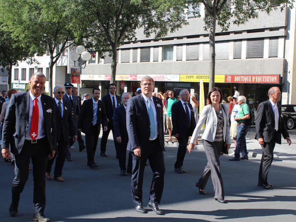 Walliser Regierungsräte marschieren, Umzug im Hintergrund.