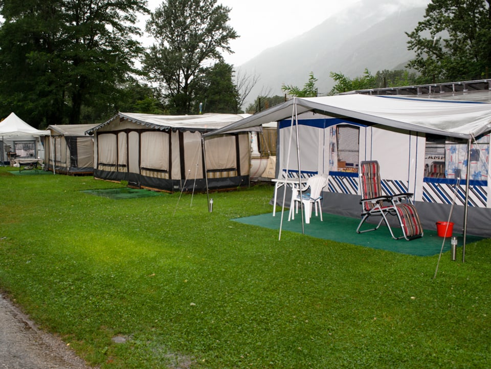 Blick auf ein paar Zelte auf dem Campingplatz in Bellinzona. Das hintere ist geschlossen, beim vorderen stehen ein paar Campingstühle unter dem Vorzelt.