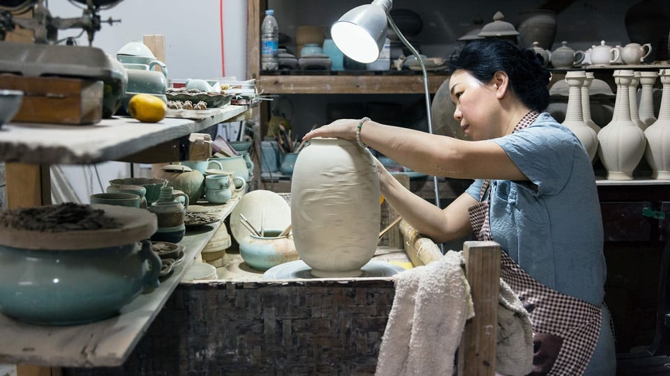 Meisterin Chen Shaoqing in ihrer Werkstatt beim Signieren einer Vase. 