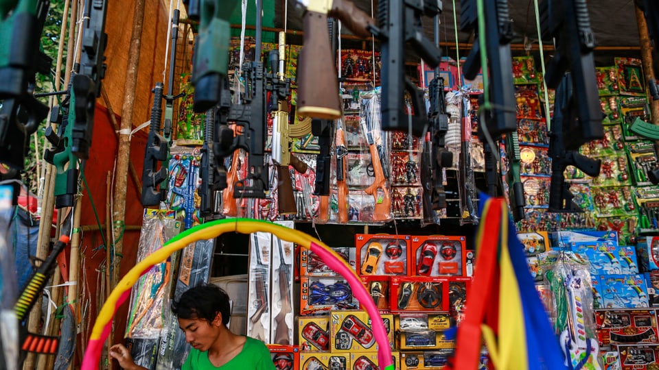 Ein Mann verkauft in einem Township nahe Yangon Spielzeug, aber auch Waffen.