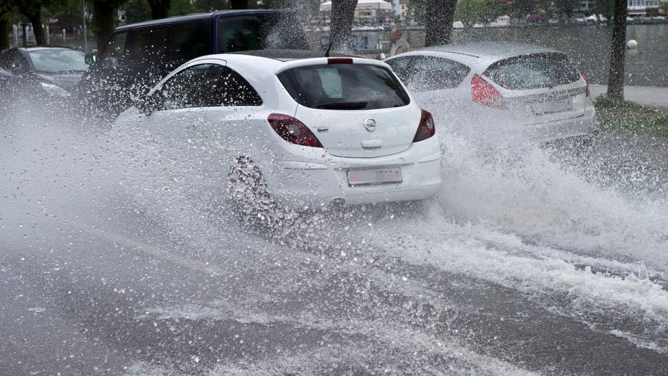 Autos fahren auf einer überfluteten Strasse im Tessin.