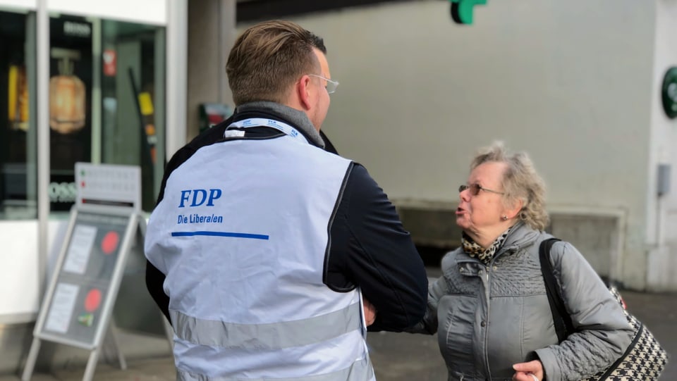 Ein Wahlkampfhelfer der FDP spricht mit einer älteren Frau. 