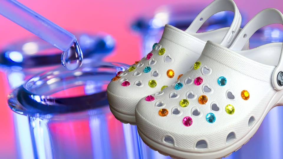 Weisse Clogs mit bunten Perlen, im Hintergrund sindLaborgefässe zu sehen