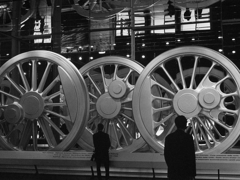Besucher begutachten riesige Räder aus Stahl für Dampflokomotiven.