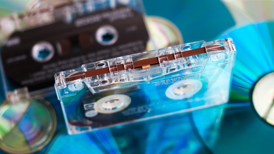 Eine durchsichtige Audio-Kassette auf einem Stapel Compact Discs.