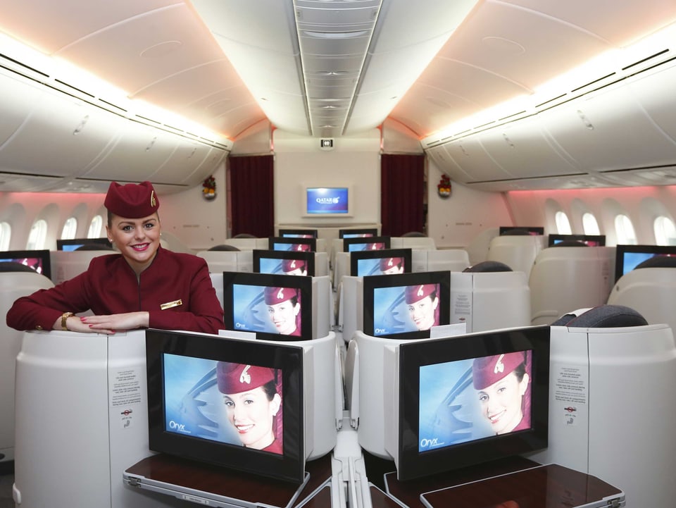 Stewardess steht hinter einem Bildschirm in der Business-Class.