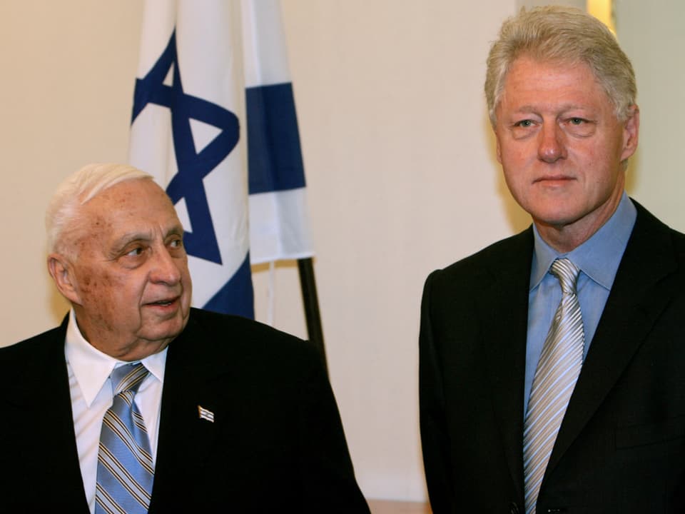 Ariel Sharon betrachtet den neben ihn stehenden Bill Clinton.