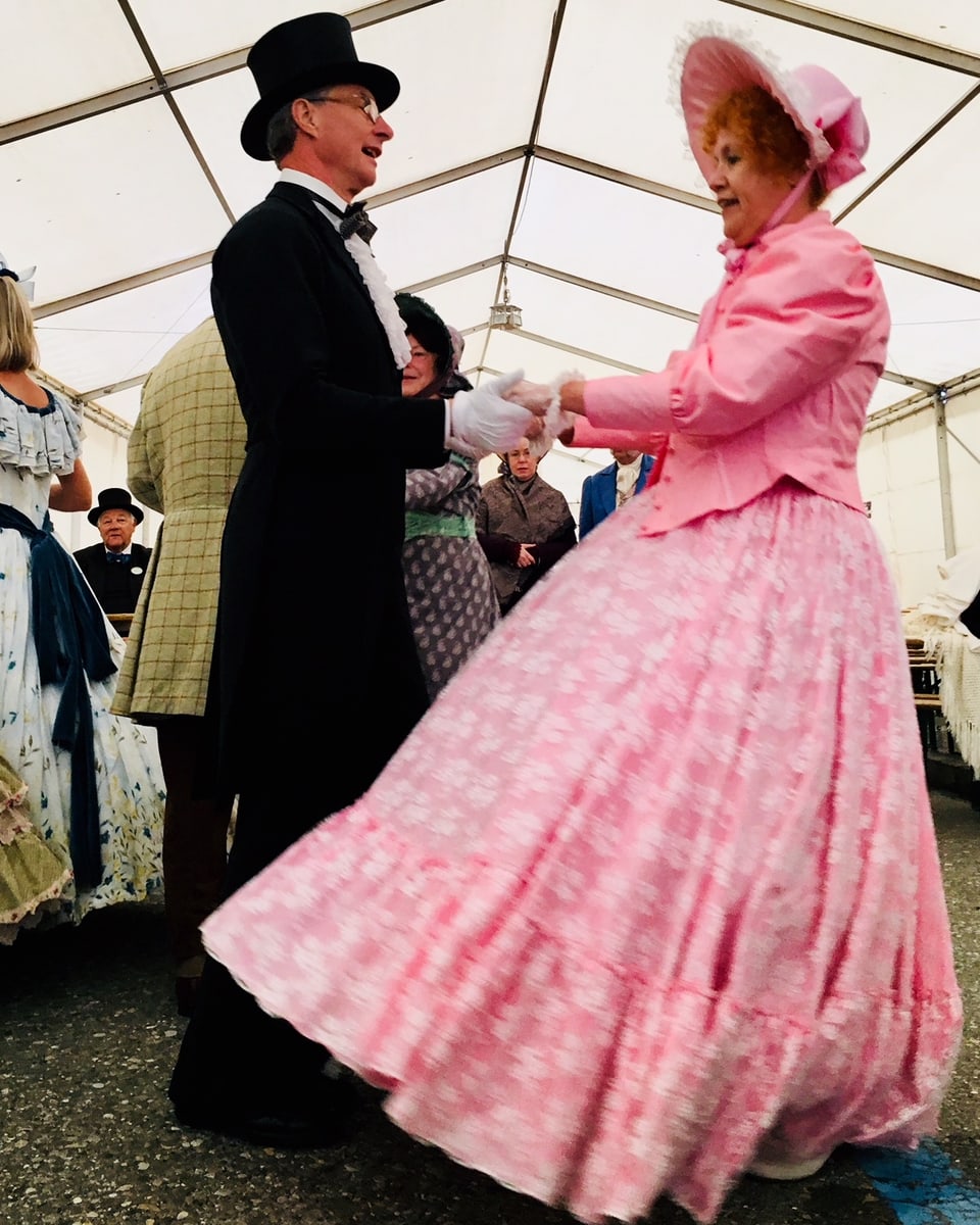 Mann und Frau in Biedermeier-Kostümen tanzen