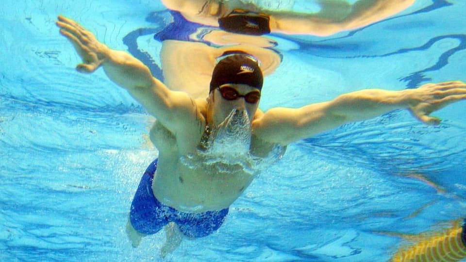 Mann schwimmt Brust im Schwimmbad mit Kopf unter dem Wasser.