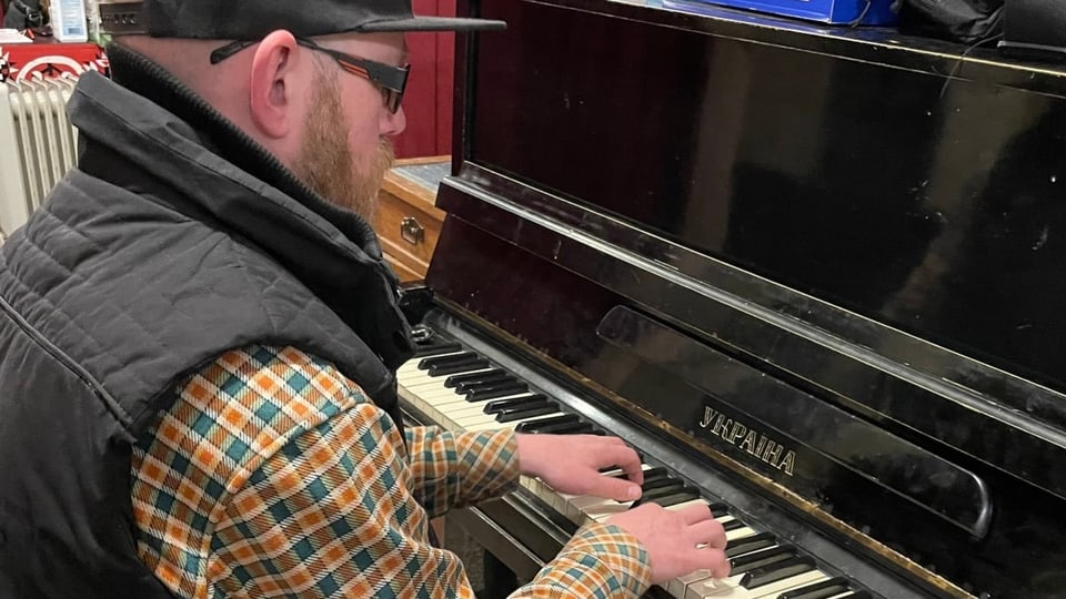 Ein Mann mit Bart und Brille spielt Klavier.