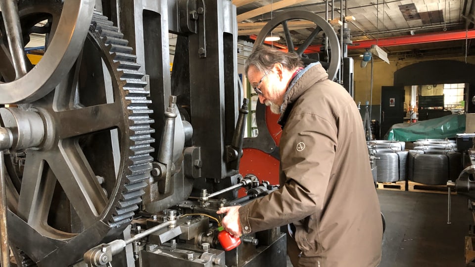 Ein Mann mit einem Ölfläschen giesst Öl in eine Maschine. 